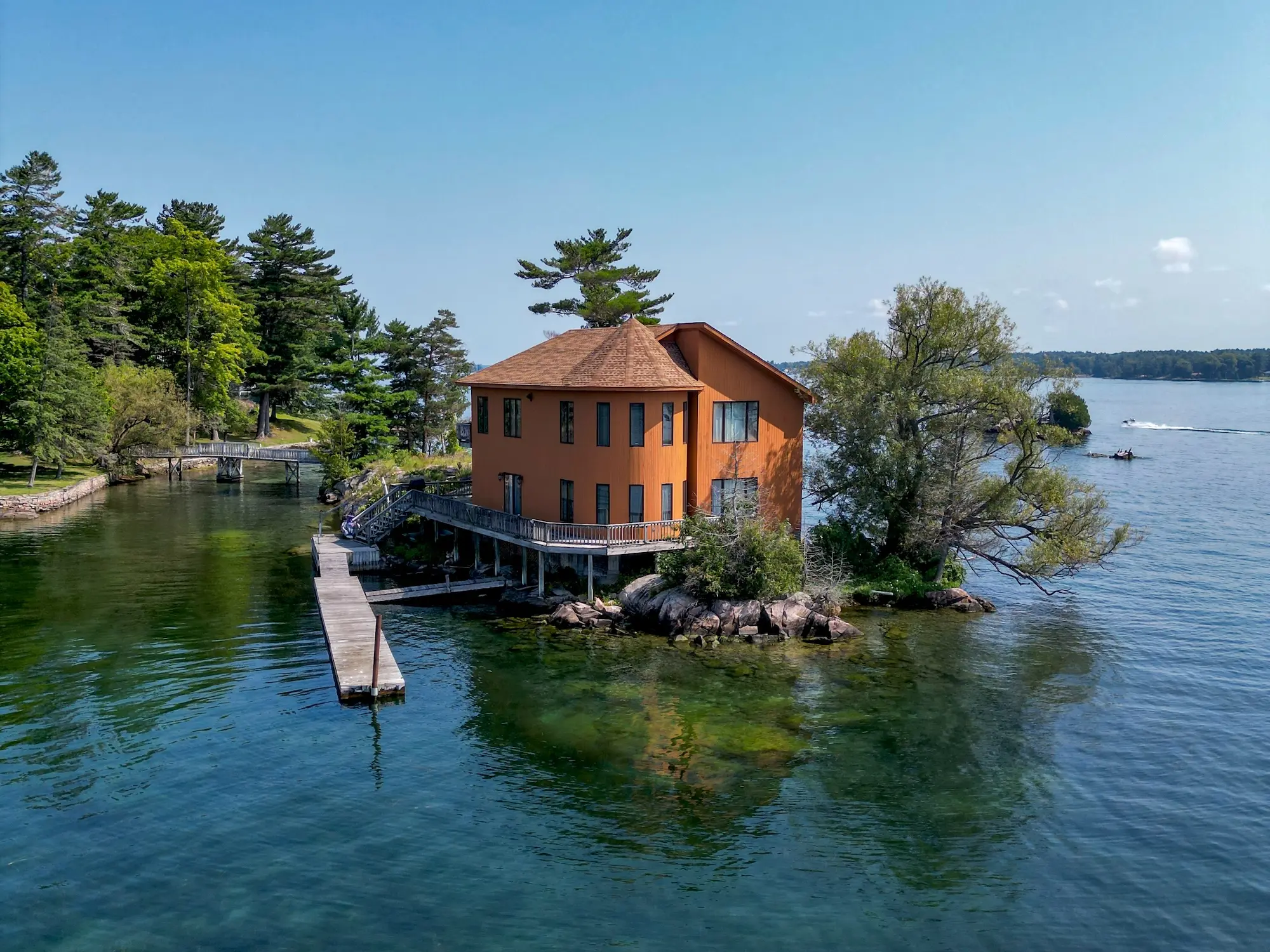 Water-level view of the octagonal cedar house with its conical roof, wraparound deck and pilings